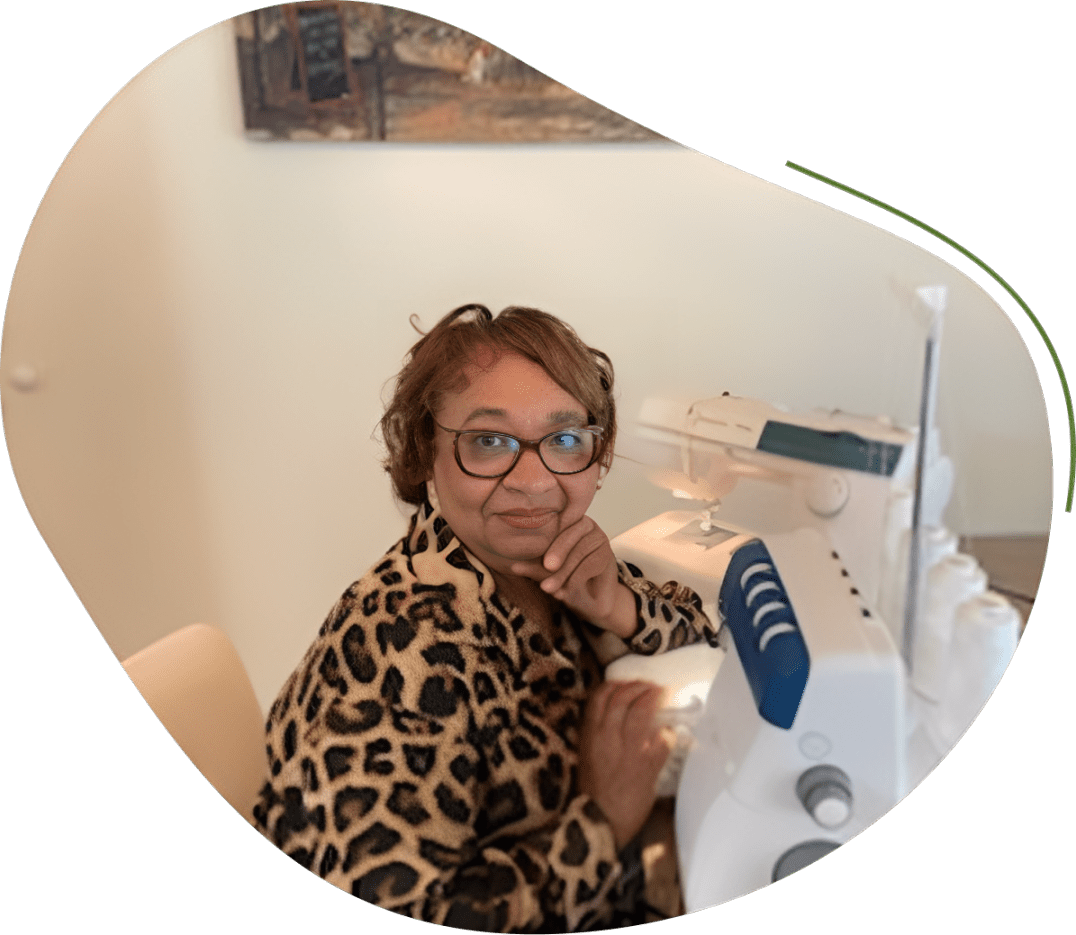 Woman sewing with a white machine, wearing leopard print sweater.